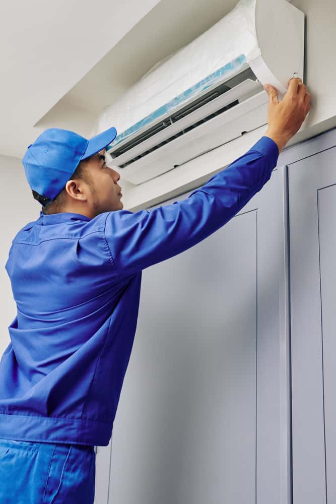 technician working on wall mounted ac unit.