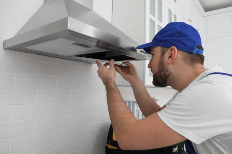 Worker Repairing Modern Cooker Hood In Kitchen